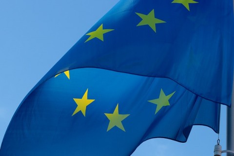 Ireland and EU flags seen from below against a blue sky