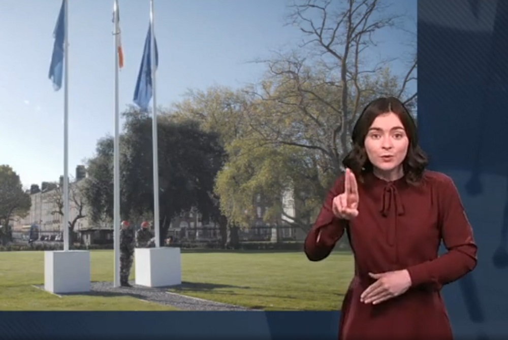 Video still of flagposts on Leinster Lawn with ISL interpreter in the foreground